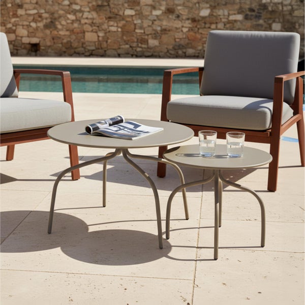 Set aus zwei runden Metall-Beistelltischen in einem Garten-Loungebereich mit Holzsesseln und grauen Polstern an einem Pool.