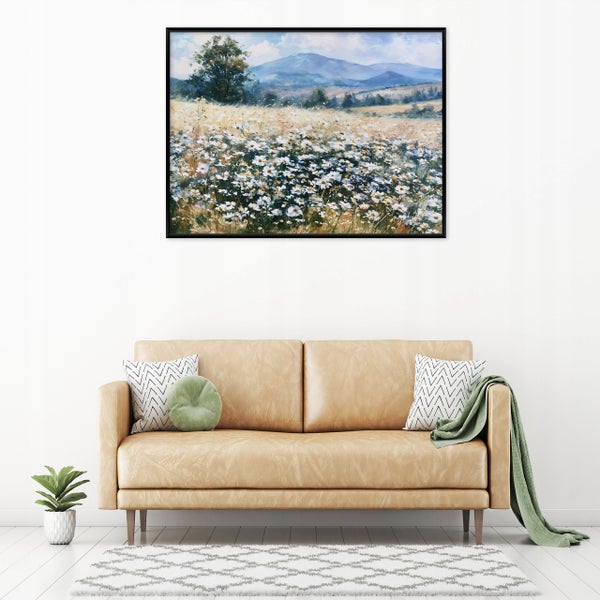 Wandbild mit Landschaftsmotiv von einer Blumenwiese und Bergen in einem schwarzen Rahmen über einem Ledersofa im Wohnzimmer.
