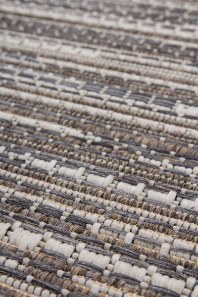 Nahaufnahme eines flachgewebten Teppichs mit geometrischem Muster in Grau, Beige und Weiß für den Innen- und Außenbereich.