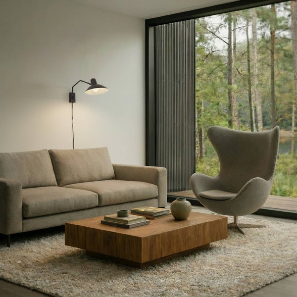 Wohnzimmer mit Sofa, Sessel, Holztisch, Teppich, Fenster und Wandlampe