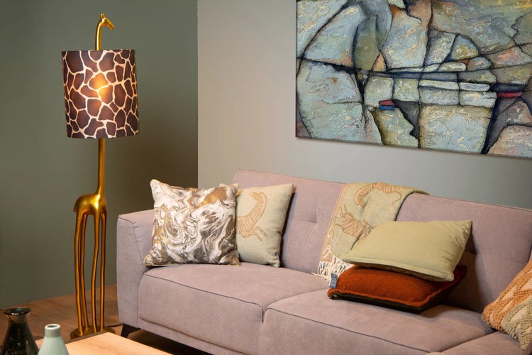 Wohnzimmer-Szene mit Sofa, Kissen, Gemälde und Stehlampe in Form einer goldenen Giraffe