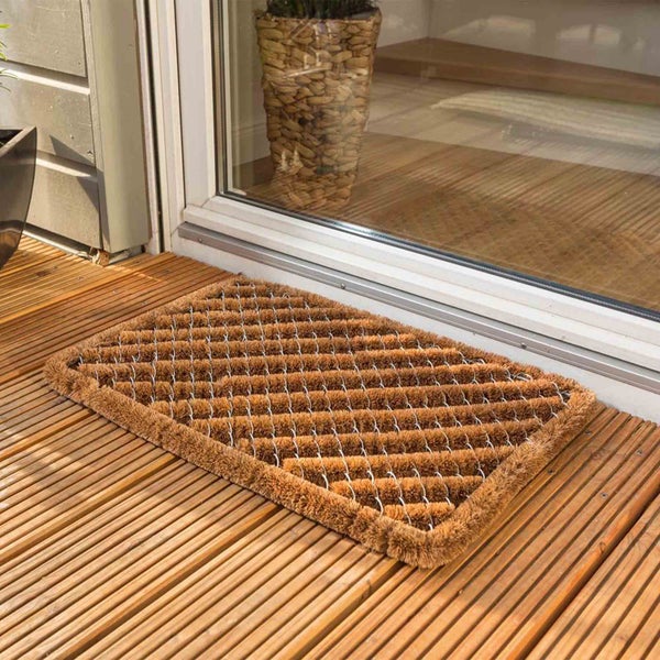 Fußmatte aus Kokosfasern mit Drahtgitter vor einer Tür auf einem Holzdeck