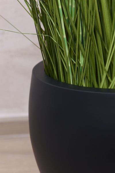 Künstliches Gras in einem runden mattschwarzen Pflanzkübel.