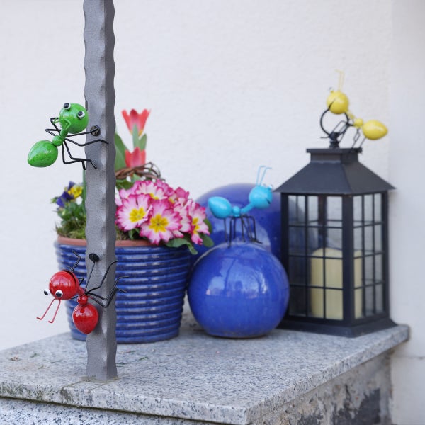Dekorative Gartenszene mit Metallameisen, Pflanztopf, Kugeln und Windlicht