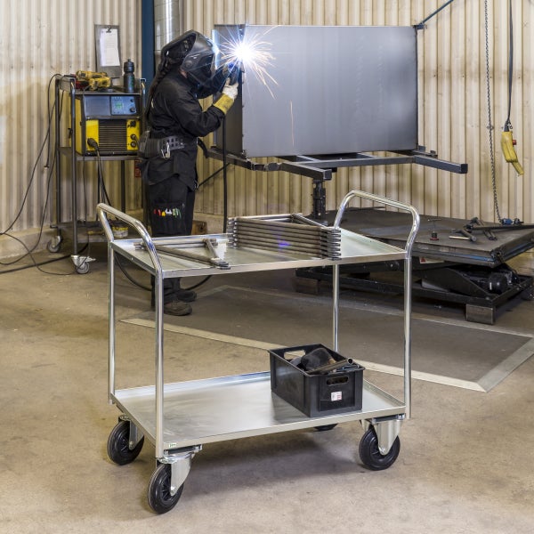 Werkstatt mit Schweißer, Schweißtisch und Werkstattwagen mit zwei Ablagen