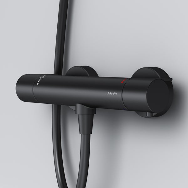 Matte schwarze Duscharmatur mit Wandanschluss und Halterung für Brauseschlauch und Duschstange.
