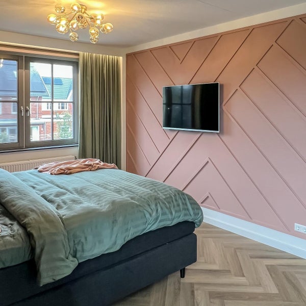 Schlafzimmer mit Doppelbett, Fernseher und dekorativer Wandgestaltung