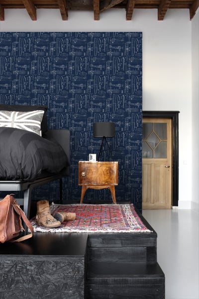 Schlafzimmer mit dunkelblauer Tapete mit Flugzeugmuster, Bett, Nachttisch und Teppich.