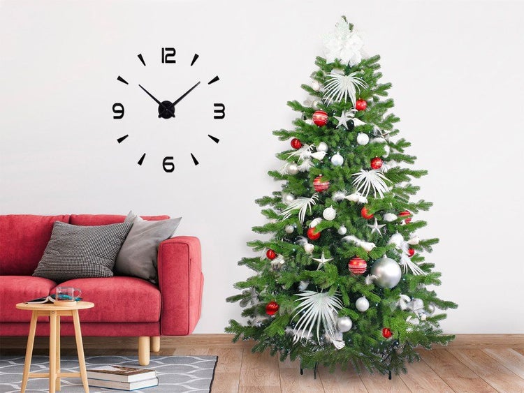 Weihnachtsbaum mit Christbaumschmuck und einer modernen Wanduhr in einem weihnachtlich dekorierten Wohnzimmer mit Sofa.