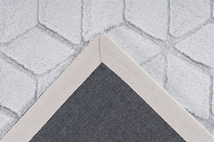 Detailansicht eines weichen hellgrauen Teppichs mit geometrischem Muster und rutschhemmender Rückseite.