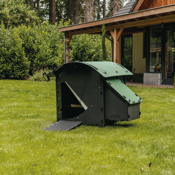 Moderner Hühnerstall aus schwarzem und grünem Kunststoff mit Nistkasten und Rampe auf einem Rasen neben einem Haus, funktionales Design.