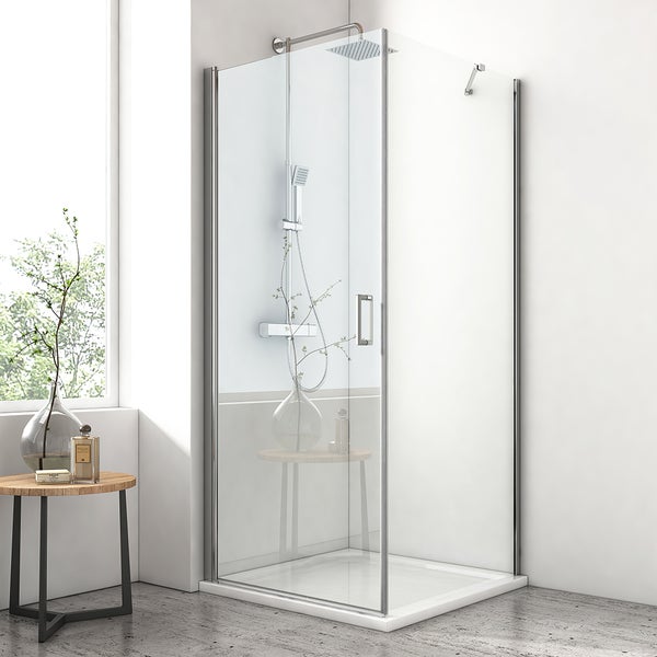 Moderne Eckduschkabine aus Klarglas mit chromfarbenen Profilen, Regendusche und weißer Duschwanne in einem hellen Badezimmer.
