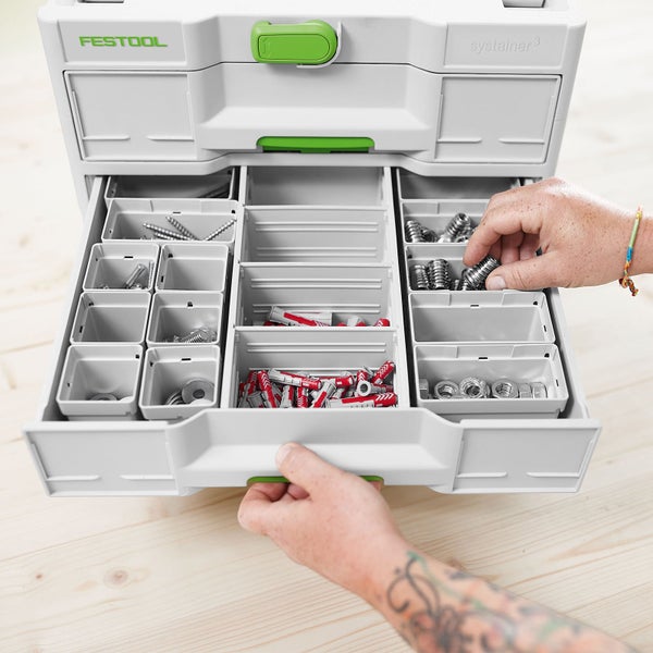 Person entnimmt Kleinteile aus einem Festool Systainer3 Organizer mit geöffneter Schublade und Einsatzboxen auf einer Holzoberfläche.