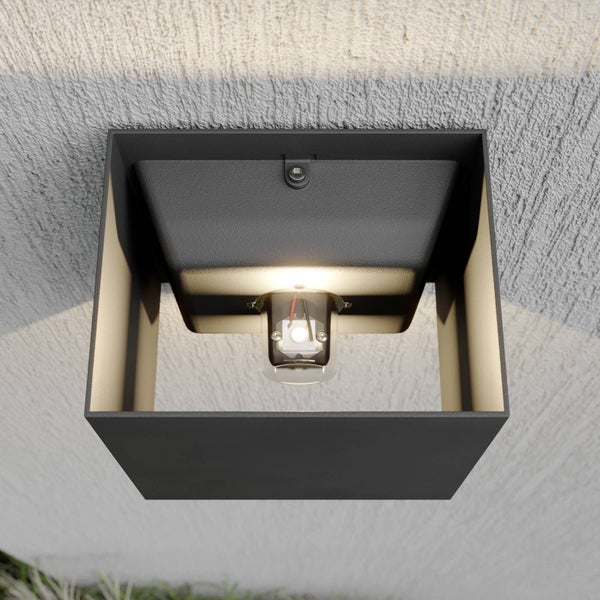 Quadratische schwarze Außenwandleuchte aus Metall mit Leuchtdiode, montiert an einer strukturierten Wand.