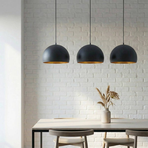 Drei Pendelleuchten aus Metall über einem Esstisch