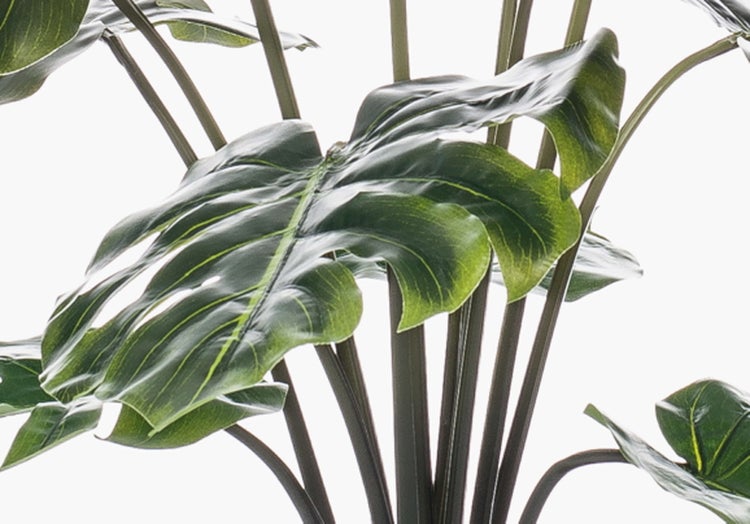 Künstliche Orchidee mit grünen Blättern, Luftwurzeln und einem Bambusstab.