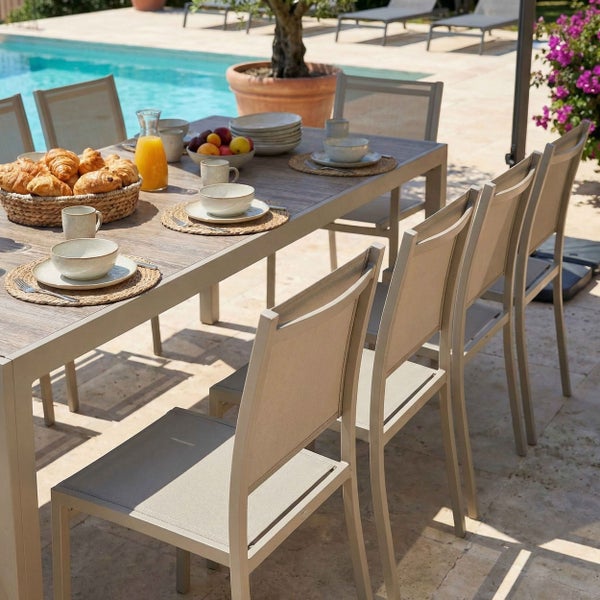 Moderner Garten-Essbereich mit Metalltisch und Textilstühlen auf einer Terrasse am Pool, hell und einladend gestaltet für das Frühstück.