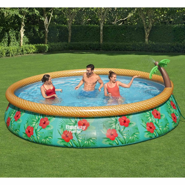 Runder Bestway Fast Set Pool mit tropischem Blumenmuster und aufblasbarem Palmen-Wassersprüher im Garten mit drei Personen.