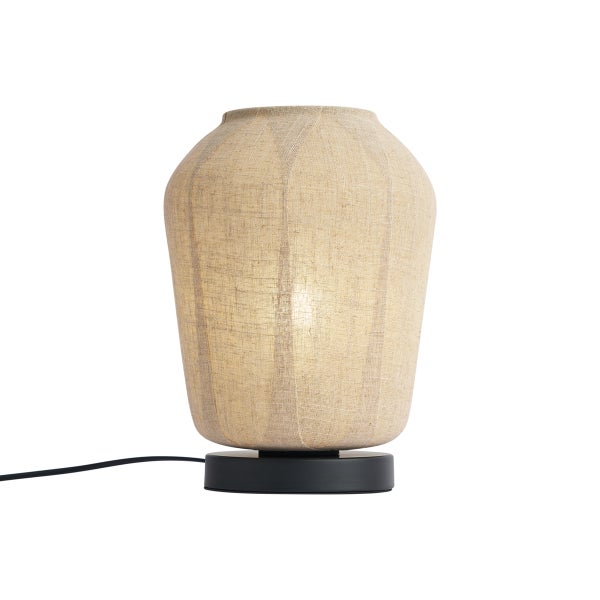 Tischleuchte mit beigem Stoffschirm aus Leinen und schwarzem Standfuß, beleuchtet.