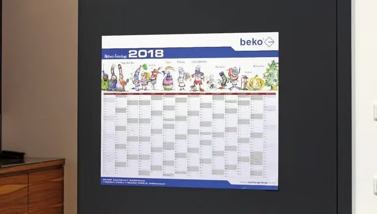 Wandkalender für das Jahr 2018 von beko mit illustrierten Figuren an einer dunklen Wand.