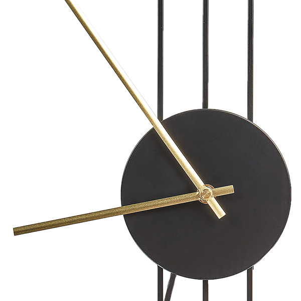 Detailaufnahme einer minimalistischen Wanduhr mit goldfarbenen Zeigern und schwarzem Zifferblatt vor vertikalen Metallstäben.