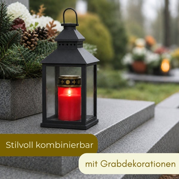 Schwarze Grablaterne aus Metall und Glas mit brennender Grabkerze auf einem Granitgrabstein neben einem Gesteck mit Tannenzweigen.