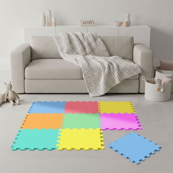 Bunte Puzzle-Spielmatte aus Schaumstoff für Kinder in einem hellen, aufgeräumten Wohnzimmer vor einem Sofa mit Strickdecke.