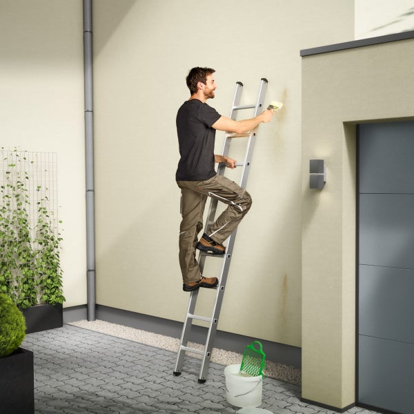 Mann auf einer Leiter beim Streichen einer Hauswand mit einem Pinsel.