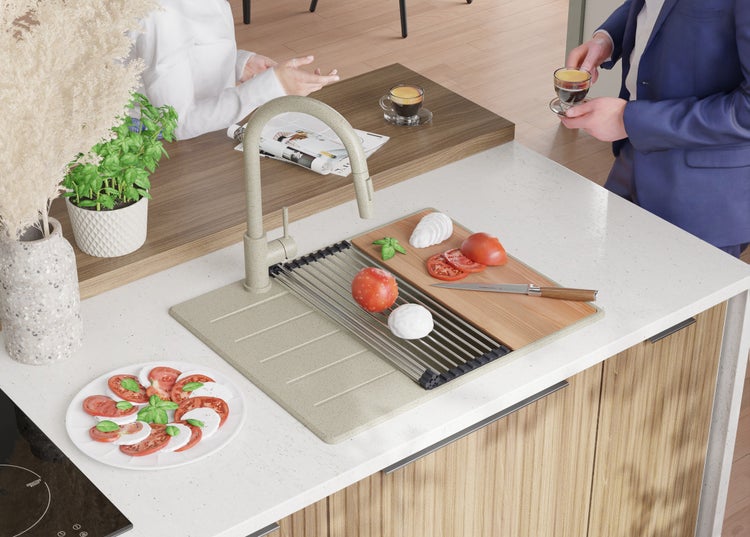 Küchenspüle mit Armatur, Abtropfgitter, Schneidebrett, Tomaten und Mozzarella auf einer Küchentheke.