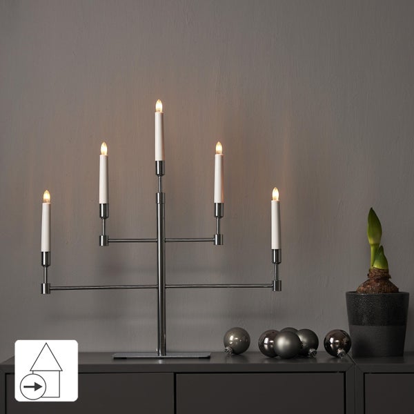 Dekorativer Kerzenleuchter mit fünf Lichtern auf einer Kommode, mit Weihnachtsbaumkugeln und einer Zimmerpflanze.