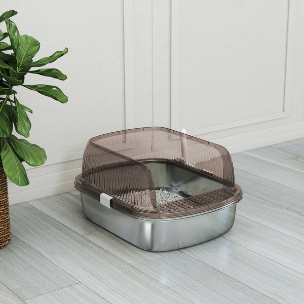 Moderne Katzentoilette mit einer Edelstahl-Wanne und einem halbtransparenten braunen Kunststoffaufsatz in einem hellen Raum neben einer Pflanze.