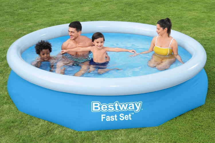 Familie mit zwei Kindern in einem runden Bestway Fast Set Pool auf einer Rasenfläche im Garten.