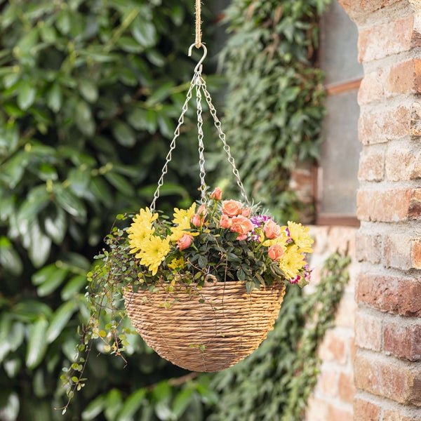 Hängeampel aus Weide mit gelben und rosafarbenen Blüten
