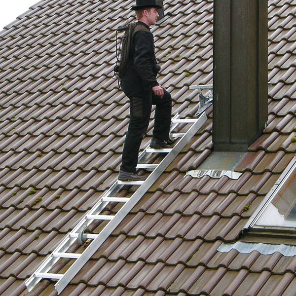 Ein Mann benutzt eine Dachleiter, um auf einem Dach mit Ziegeln zu arbeiten.