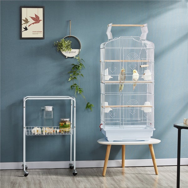 Szene mit einem Vogelkäfig auf einem Tisch, einem Servierwagen und Dekorationsgegenständen an der Wand