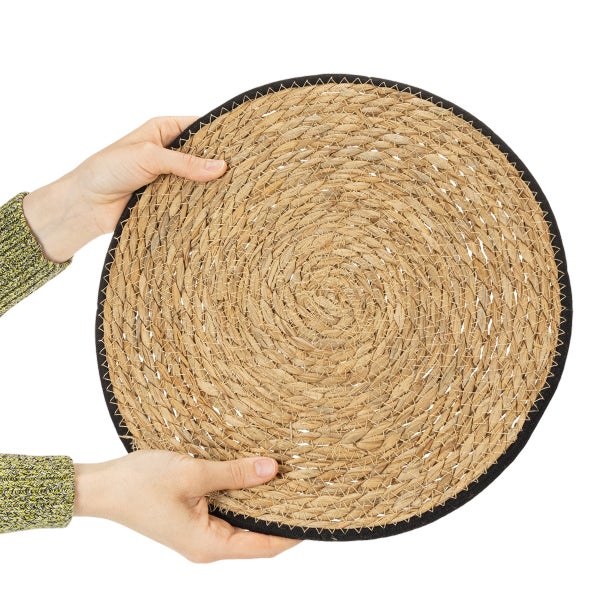Rundes Tischset aus geflochtenem Seegras mit schwarzem Rand.