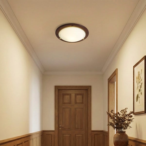 Runde Deckenleuchte mit dunklem Holzring und weißem Glas in einem hellen Flur mit Holztüren und Wandverkleidung.