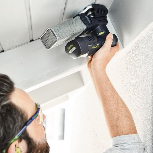 Ein Mann schleift mit einem Akku-Deltaschleifer von Festool eine Decke.
