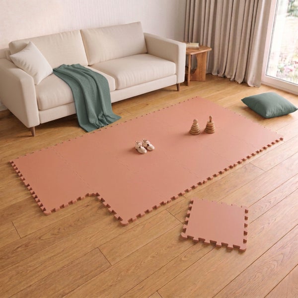 Wohnzimmer mit einer Spielmatte aus Schaumstoffelementen zum Zusammenstecken auf dem Holzboden, weicher Spielteppich für Kinder.