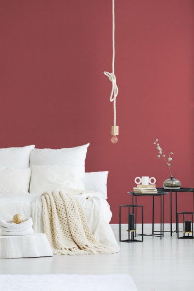 Schlafzimmer mit Bett, Nachttischen und Pendelleuchte vor einer Wand