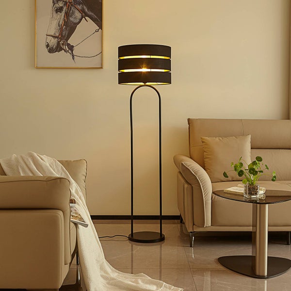 Stehleuchte mit drei schwarzen Lampenschirmen in einem Wohnzimmer.