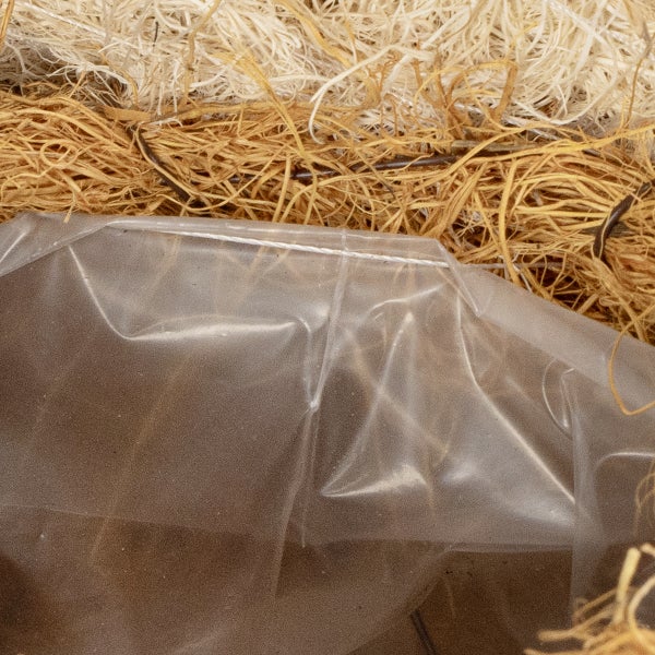 Nahaufnahme von Blumenerde und Pflanzenfasern in einer Plastikverpackung.