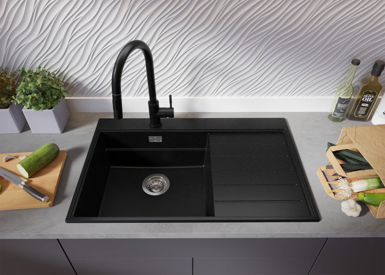 Schwarze Küchenspüle mit Abtropffläche und schwarzer Armatur auf einer Küchentheke.