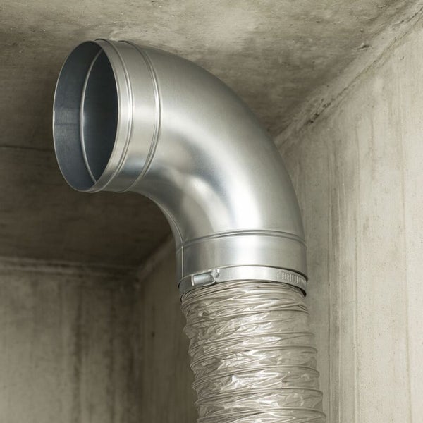 Rohrbogen aus verzinktem Stahl fuer Lueftungssysteme mit flexiblem Abluftschlauch montiert an einer Wand.