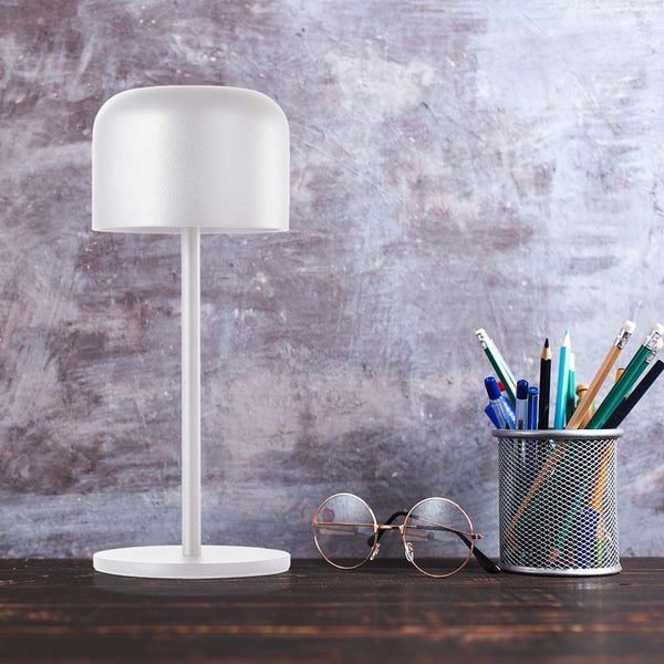 Tischleuchte neben Stifthalter und Brille auf dem Schreibtisch