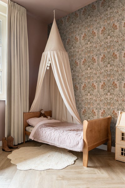 Kinderzimmer mit Himmelbett, gemusterter Tapete und Holzboden