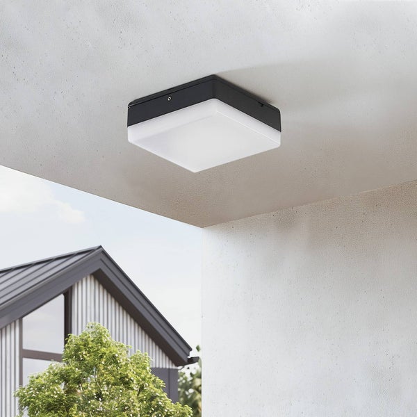 Quadratische Außen-Deckenleuchte montiert an einer Betondecke, im Hintergrund ein modernes Wohnhaus und Bäume.