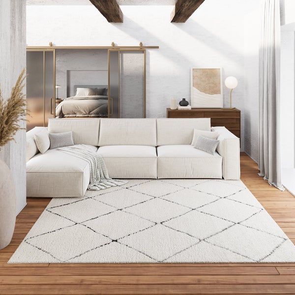 Modernes, helles Wohnzimmer mit großem hellem Ecksofa und Hochflor-Teppich mit Rautenmuster auf Holzfußboden.