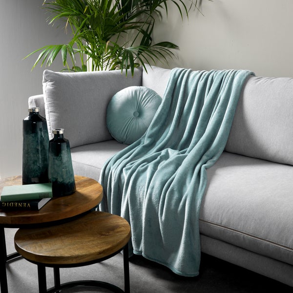 Wohnzimmer-Szene mit Sofa, Dekokissen, Tagesdecke und Beistelltischen