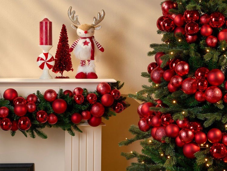 Festlich geschmückter Weihnachtsbaum und Kamin mit Kugeln und Dekofigur als weihnachtliche Raumdekoration.